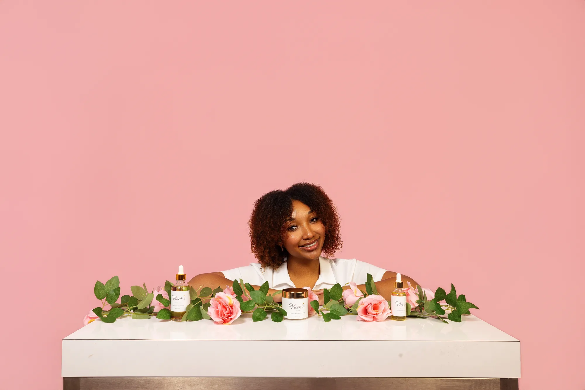 The founder of Vioré behind a table styled with all three products, roses, and eucalyptus